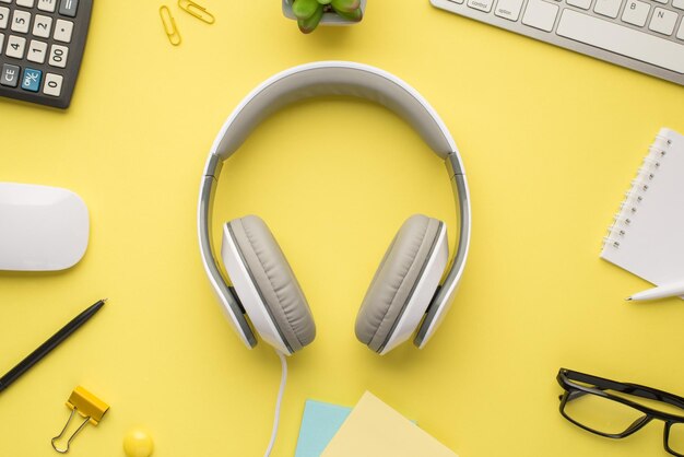 Photo ci-dessus d'un casque calculatrice plante clavier cahier stylo lunettes notes trombones et souris d'ordinateur isolé couleur vive fond jaune