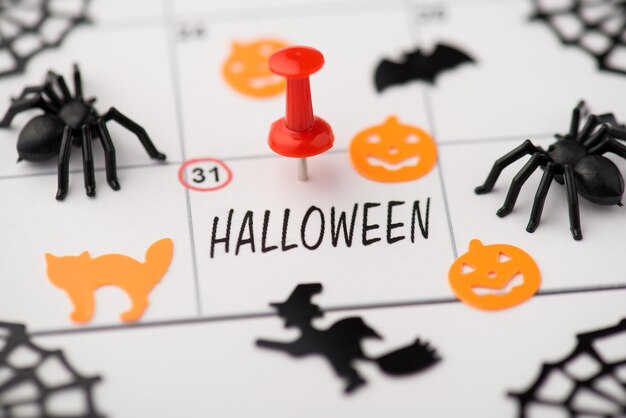 Photo ci-dessus de la date de l'étiquette 31 octobre avec broche rouge décor halloween citrouille sorcière araignée chat et chauve-souris isolés sur le fond du calendrier