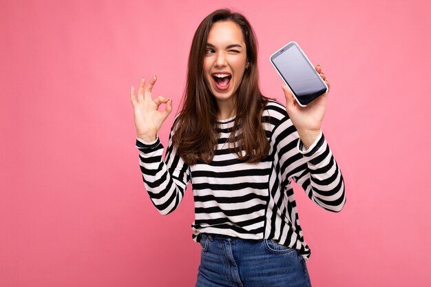 Photo D'un Clin De œil Belle Jeune Femme Heureuse Portant Un Pull Rayé Isolé Sur Fond Avec