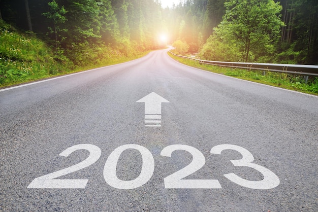 Photo conceptuelle 2023 de la route goudronnée Couverture du calendrier de l'année 2023 avec forêt d'été et route Paysage optimiste avec l'aube du soleil sur la route à venir Modèle de bannière du Nouvel An Carte de route panoramique avec l'année 2023