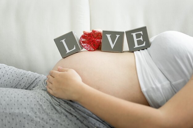 Photo conceptuelle du mot amour épelé sur des blocs sur le ventre de la femme enceinte