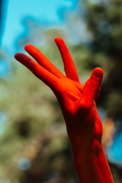 Photo photo conceptuelle, élégante main féminine en lumière rouge. fond de forêt