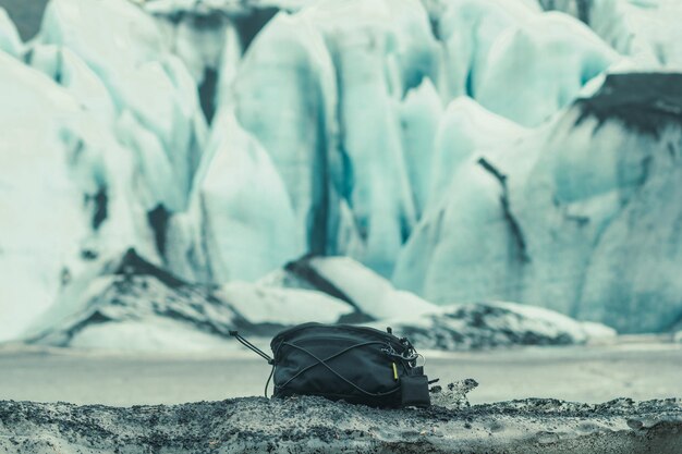 Photo une photo conceptuelle d'un sac noir en gros plan sur un terrain enneigé