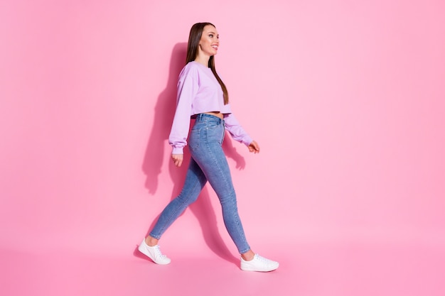 Photo de côté de profil complet du corps d'une jolie fille sympathique et sympathique aller marcher regarder bien fond rencontrer un ami week-end de vacances isolé fond de couleur rose