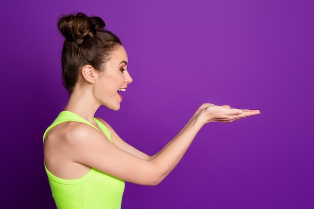 Photo de côté de profil d'une fille étonnée tenir la main de fond porter un singulet isolé sur fond de couleur violet vif