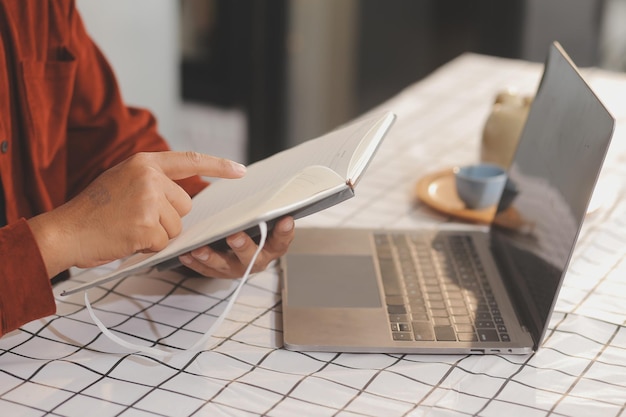 Photo coupée d'une femme d'affaires indépendante asiatique tenant une tasse de café et faisant la planification l'analyse du rapport financier le plan d'affaires l'analyse financière de l'investissement le lieu de travail