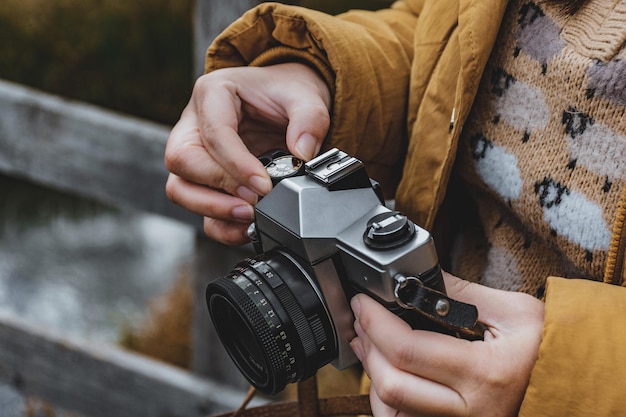 Une photo coupée en gros plan d'une femme tenant un appareil photo vintage tournant le cadran et changeant les réglages