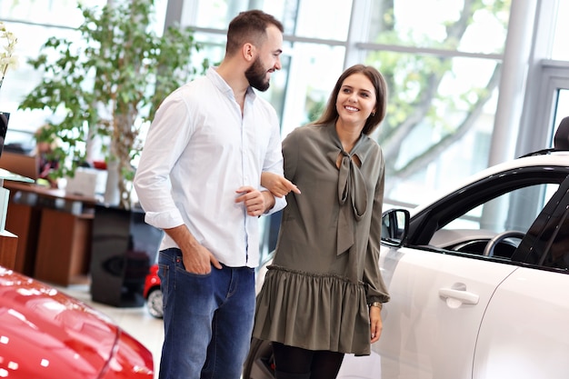 Photo d'un couple adulte choisissant une nouvelle voiture dans une salle d'exposition