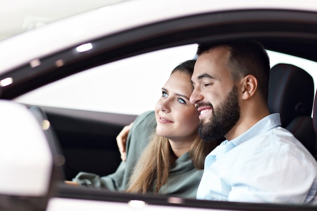 Photo d'un couple adulte choisissant une nouvelle voiture dans une salle d'exposition