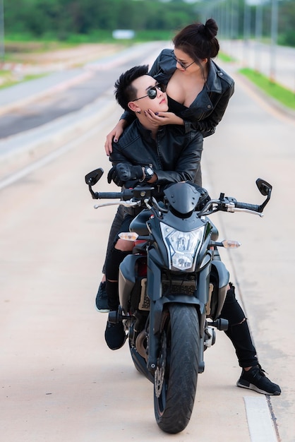 Photo d'un couple asiatique motard avec moto sur la routeBel homme et belle femme portent du cuir noir pour le conducteur sur le cheminThaïlandaisSweet nouveau couple