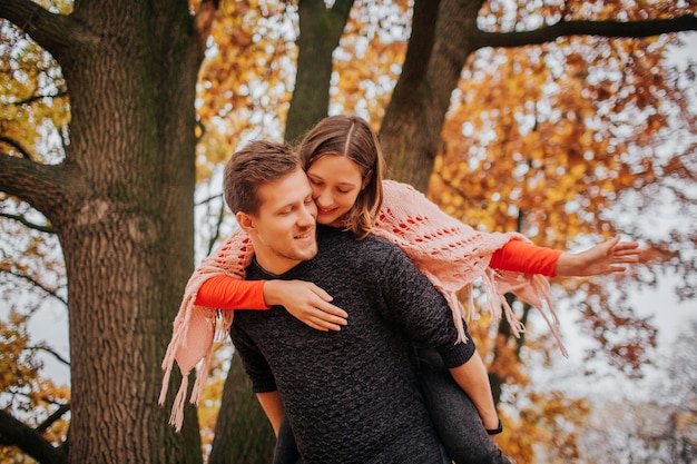 Photo d'un couple charmant, passer du temps dans le parc. Elle l'embrasse. Il la retient. L'automne à l'extérieur.