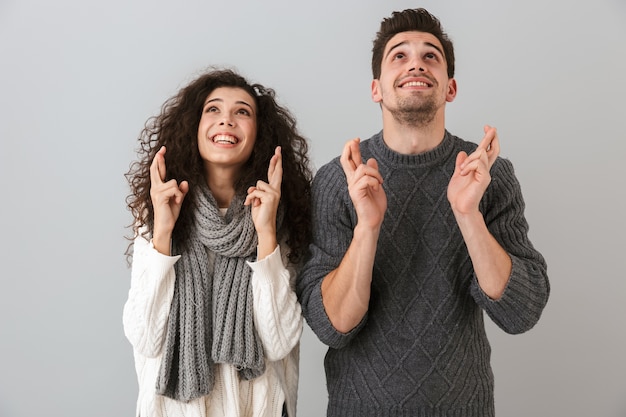 Photo De Couple Européen Homme Et Femme Souriant Et Debout Avec Les Doigts Croisés, Isolé Sur Mur Gris