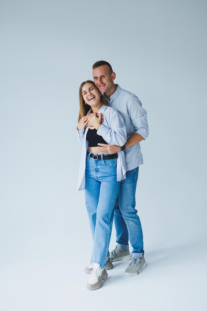 Photo d'un couple heureux portant des chemises blanches des jeans bleus isolés sur fond blanc Un homme et une femme s'embrassent sur un fond blanc
