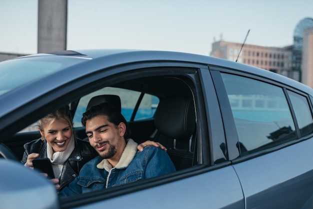 Photo d'un couple heureux utilisant un téléphone portable dans la voiture