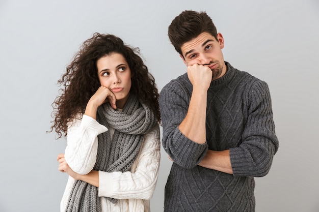 Photo de couple homme et femme s'ennuyant, soutenant leurs têtes, isolé sur mur gris