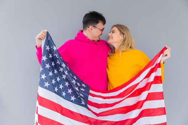 Photo d'un couple multiethnique attrayant homme et femme enveloppés dans un drapeau américain