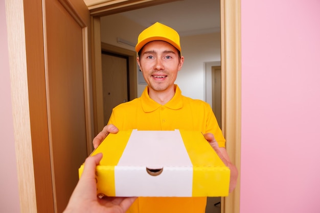 Photo d'un coursier avec une boîte à pizza dans les mains