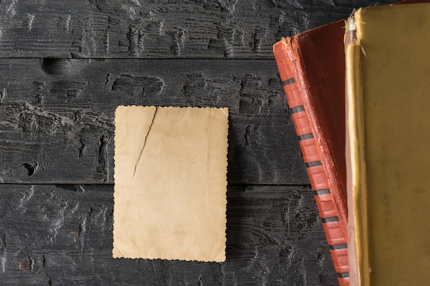 Une photo déchirée à l'envers avec des albums photo sur une table en bois noire. Papier à lettres rétro. Mise à plat.