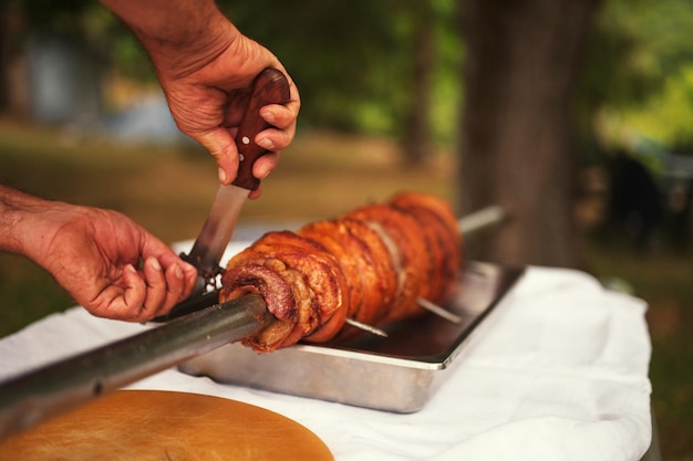 Photo photo découpée des mains d'un homme coupant de la viande de porc sur le couteau