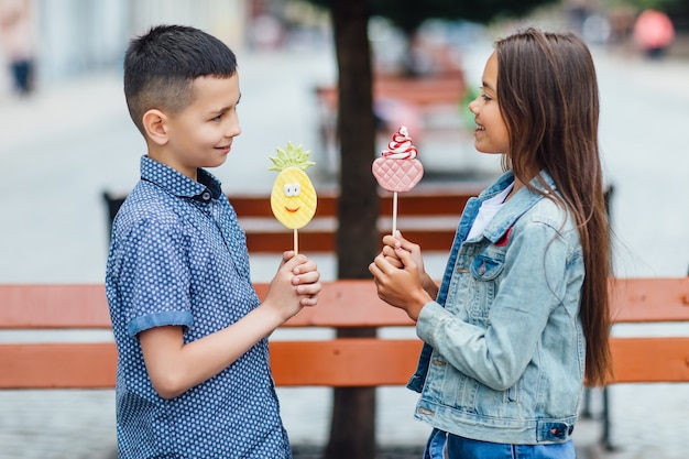 Photo de deux enfants heureux un jour d'été avec des bonbons sur les mains et souriant.