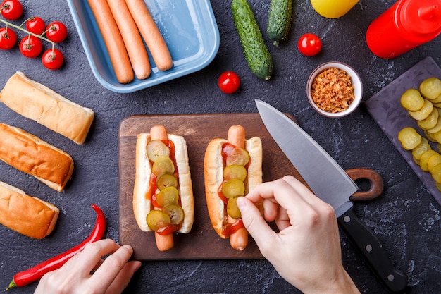 Photo sur deux hot-dogs sur une planche à découper sur une table avec des mains humaines