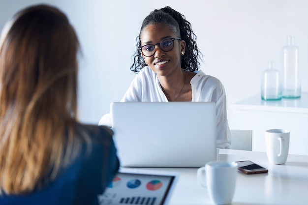 Photo De Deux Jolies Jeunes Femmes D'affaires Travaillant Avec Une Tablette Numérique Et Un Ordinateur Portable Au Bureau.