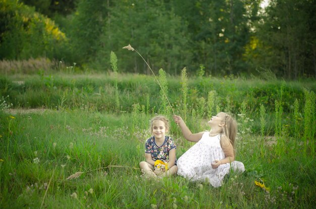 Photo de deux petites meilleures amies filles jouant assis dans le champ