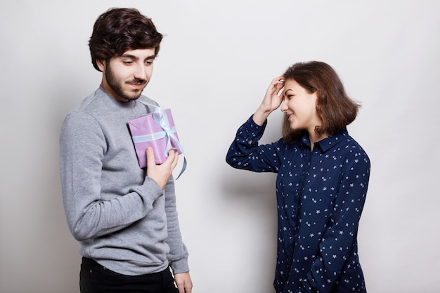 photo de deux vrais amis. gars élégant va présenter à son ami un cadeau. heureuse jeune femme va recevoir un cadeau. jeune hipster tenant une boîte-cadeau dans ses mains.