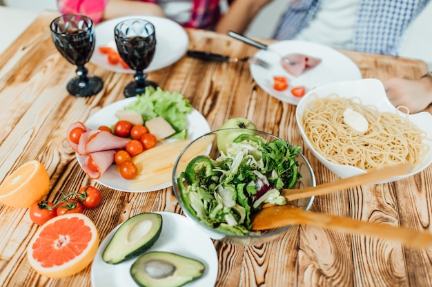 Photo d'un dîner romantique à la maison, couple faisant des macaronis et de la salade