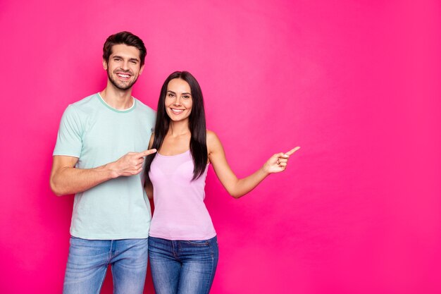 Photo de drôle de couple guy et dame indiquant les doigts à l'espace vide conseillant le vendredi noir shopping porter des vêtements décontractés fond de couleur rose vif isolé