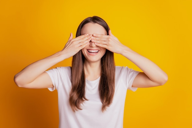 Photo de drôle de dame surprise les mains couvrent les yeux portent un t-shirt blanc posant sur fond jaune