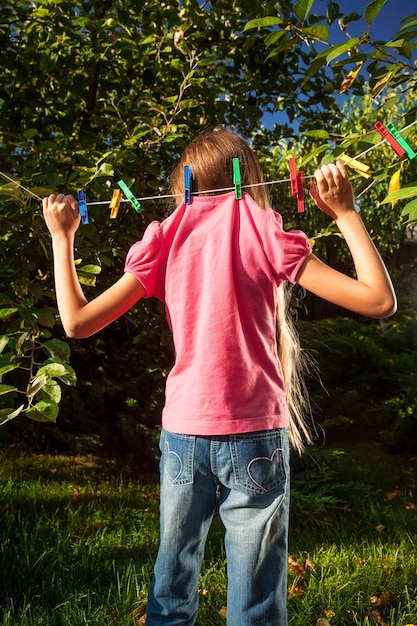 Photo drôle de jeune fille accrochée à une corde à linge au jardin