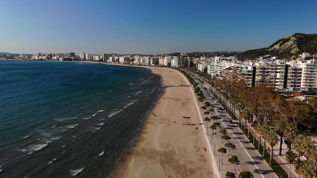 Photo de drone de la plage par une journée ensoleillée avec des arbres et de l'eau bleue