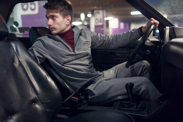 Photo du côté du conducteur masculin regardant en arrière alors qu'il était assis dans la voiture