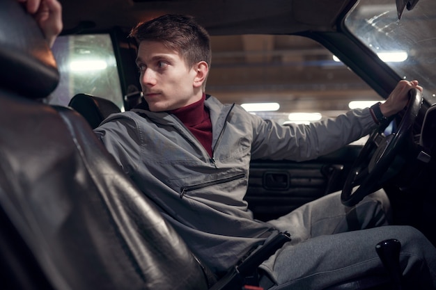 Photo du côté de l'homme conducteur regardant en arrière alors qu'il était assis dans la voiture