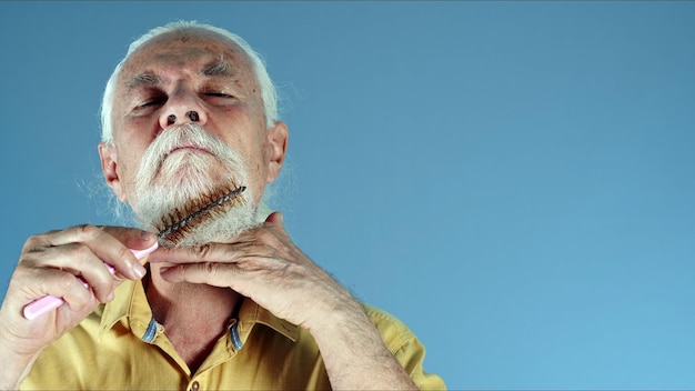 Photo du vieil homme peignant sa barbe blanche