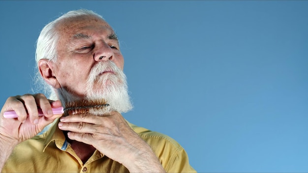 Photo du vieil homme peignant sa barbe blanche
