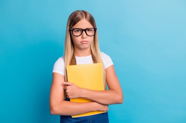 Photo d'une élève triste ne veut pas faire ses devoirs porter des lunettes tenir un livre isolé sur fond de couleur bleu pastel