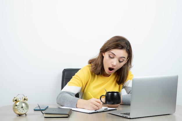 Photo d'une employée de bureau assise au bureau avec un ordinateur portable. Photo de haute qualité