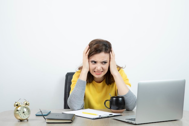 Photo d'une employée de bureau assise au bureau avec un ordinateur portable. Photo de haute qualité