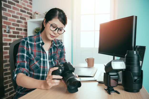 photo d'entreprise féminine sérieuse réussie faisant une femme tenant une photo de travail d'examen de caméra et assise sur un bureau prêt à être transporté pour la retouche d'édition.