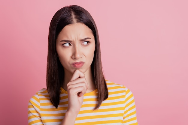 Photo de l'envie douteuse dame regarde côté espace vide doigt menton froncement de sourcils visage méfiant sur fond rose