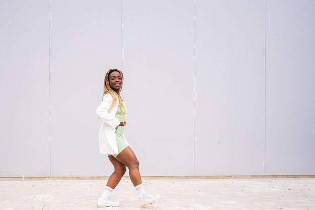 Photo avec espace de copie d'une femme noire dansant à côté d'un mur urbain