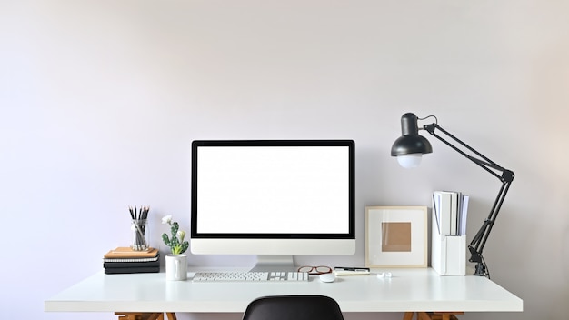 Photo de l'espace de travail contemporain. Moniteur à écran blanc blanc sur un bureau de travail moderne. Équipement sur table. Concept de bureau moderne.