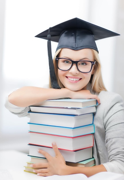 photo d'étudiant heureux en graduation cap avec pile de livres