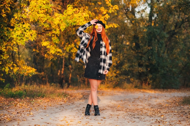 Photo extérieure d'un beau modèle féminin dans des vêtements à la mode marchant dans le parc un jour d'automne