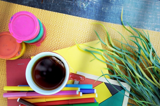 Photo extérieure d'un bureau d'art avec des feutres de couleur, une tasse de café et des peintures