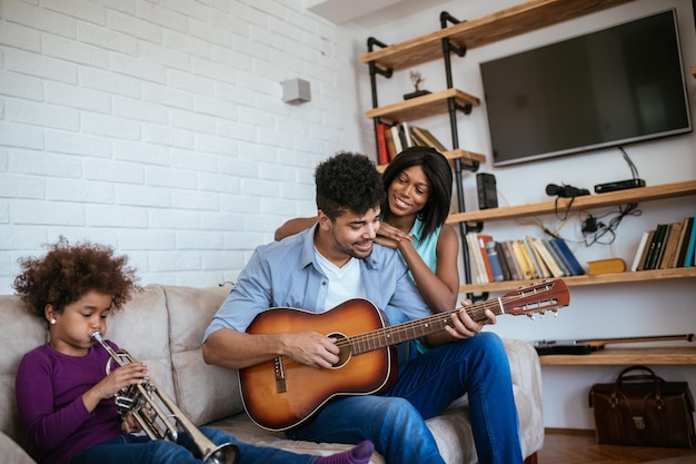 Photo d'une famille afro-américaine jouant des instruments de musique à la maison.