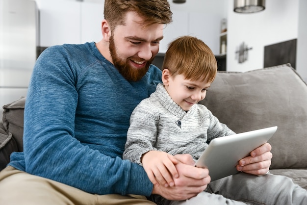 Photo de famille joyeuse utilisant une tablette à l'intérieur.