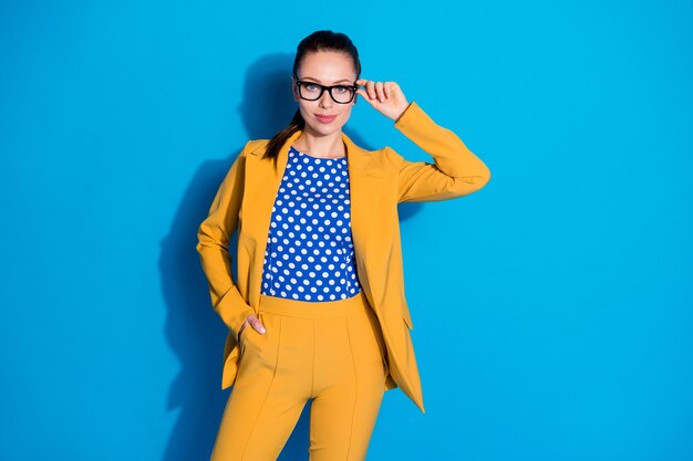 Photo d'une femme d'affaires attrayante, travailleur prospère, tenir des lunettes tactiles à la main, une bonne vue, porter un costume de blazer jaune, une chemise chemisier en pointillé, un fond de couleur bleu clair